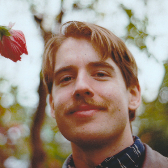 Jacob Szutka headshoot: outdoors, smiling at the camera